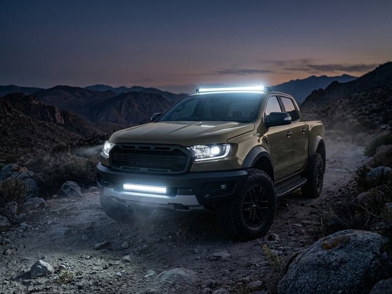 Rampe LED droite spécialement conçue pour les 4x4 allumée sur un pick-up Toyota Tacoma en franchissement rocheux nocturne, faisceau longue portée puissant
