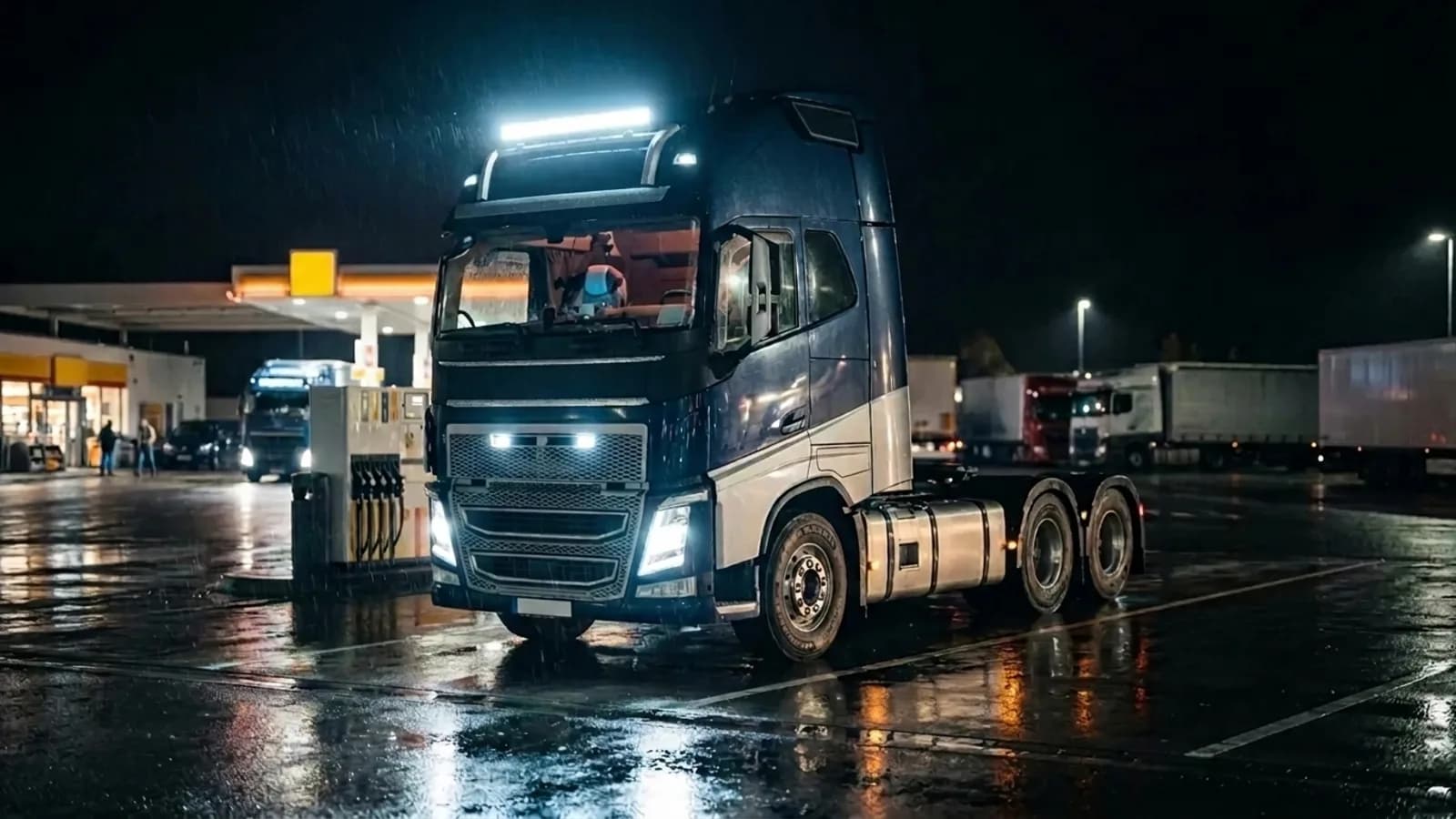 Camion poids lourd Volvo FH 24V à la station-service de nuit sous la pluie, barre LED toit allumée