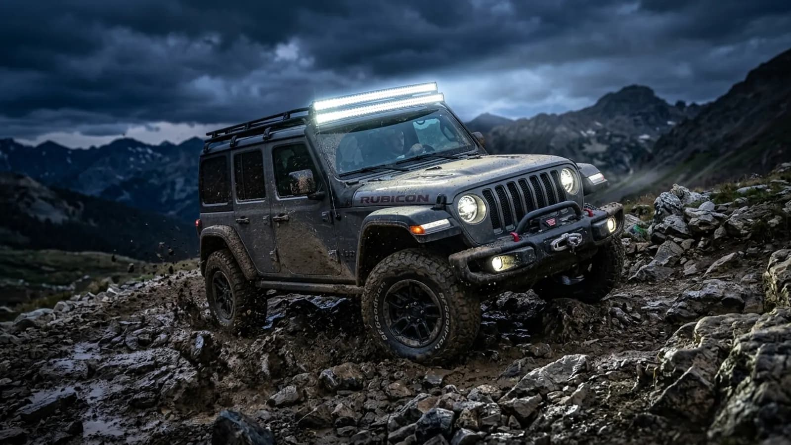 Jeep Wrangler Rubicon en franchissement rocheux nocturne avec barre LED incurvée allumée sur galerie de toit