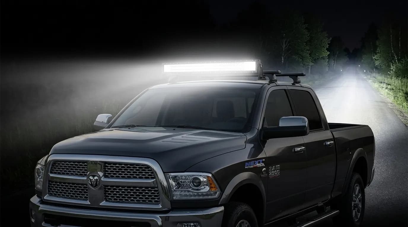 Dodge Ram de nuit sur route forestière, barre LED Next-Tech du toit allumée éclairant puissamment la route