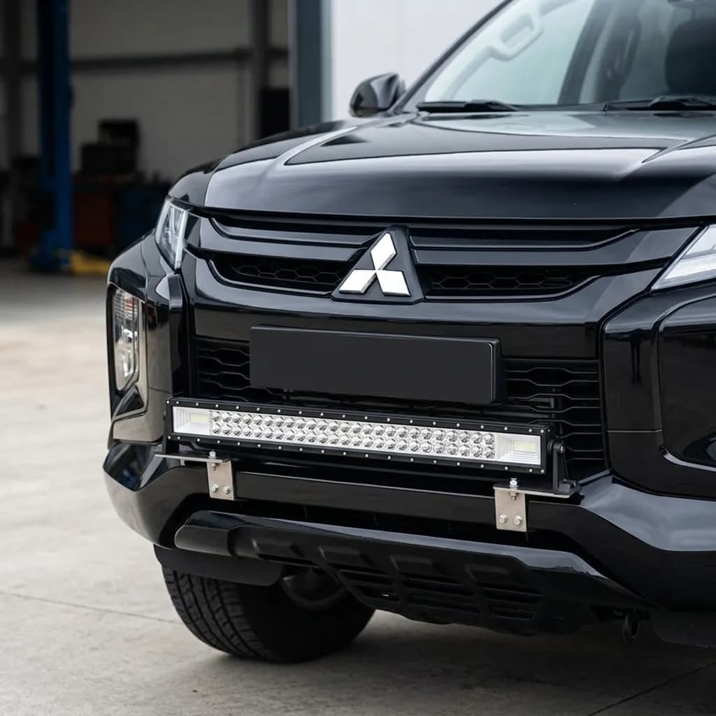 Face avant d'un Mitsubishi L200 noir avec une barre LED Next-Tech intégrée dans la calandre, en atelier