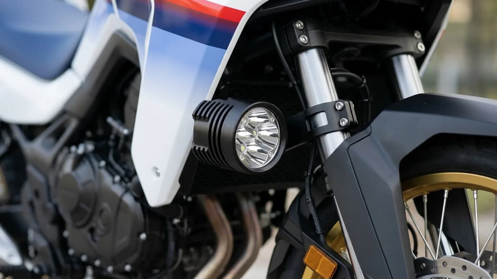 Détail du collier de fixation d'un feu additionnel LED Next-Tech sur la fourche de la Honda Transalp 750