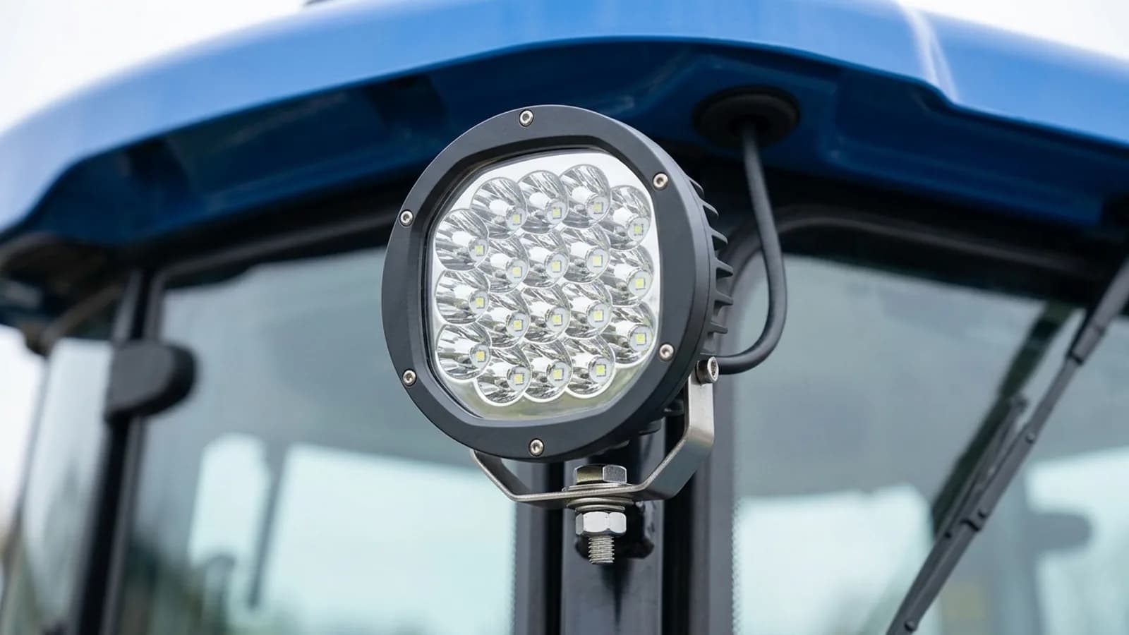 Détail d'un phare de travail LED 90W Next-Tech fixé en bord de toit d'un tracteur New Holland