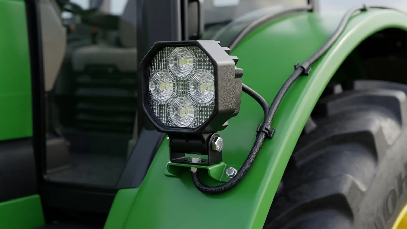 Détail d'un phare de travail LED carré Next-Tech fixé sur le garde-boue arrière d'un tracteur John Deere