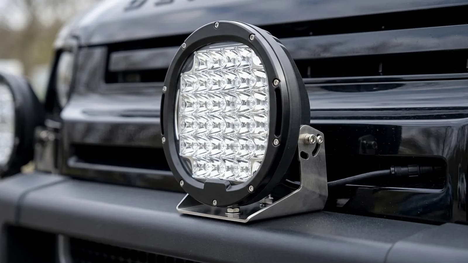 Détail d'un phare rond LED 185W Next-Tech monté sur le pare-chocs avant d'un Land Rover Defender 110