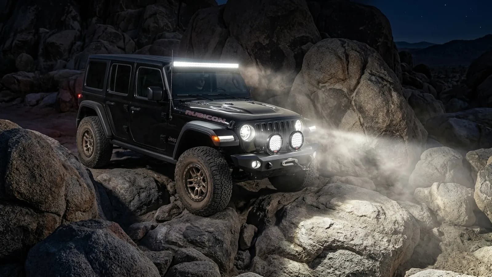 Jeep Wrangler Rubicon en franchissement nocturne, barre LED et phares ronds Next-Tech allumés