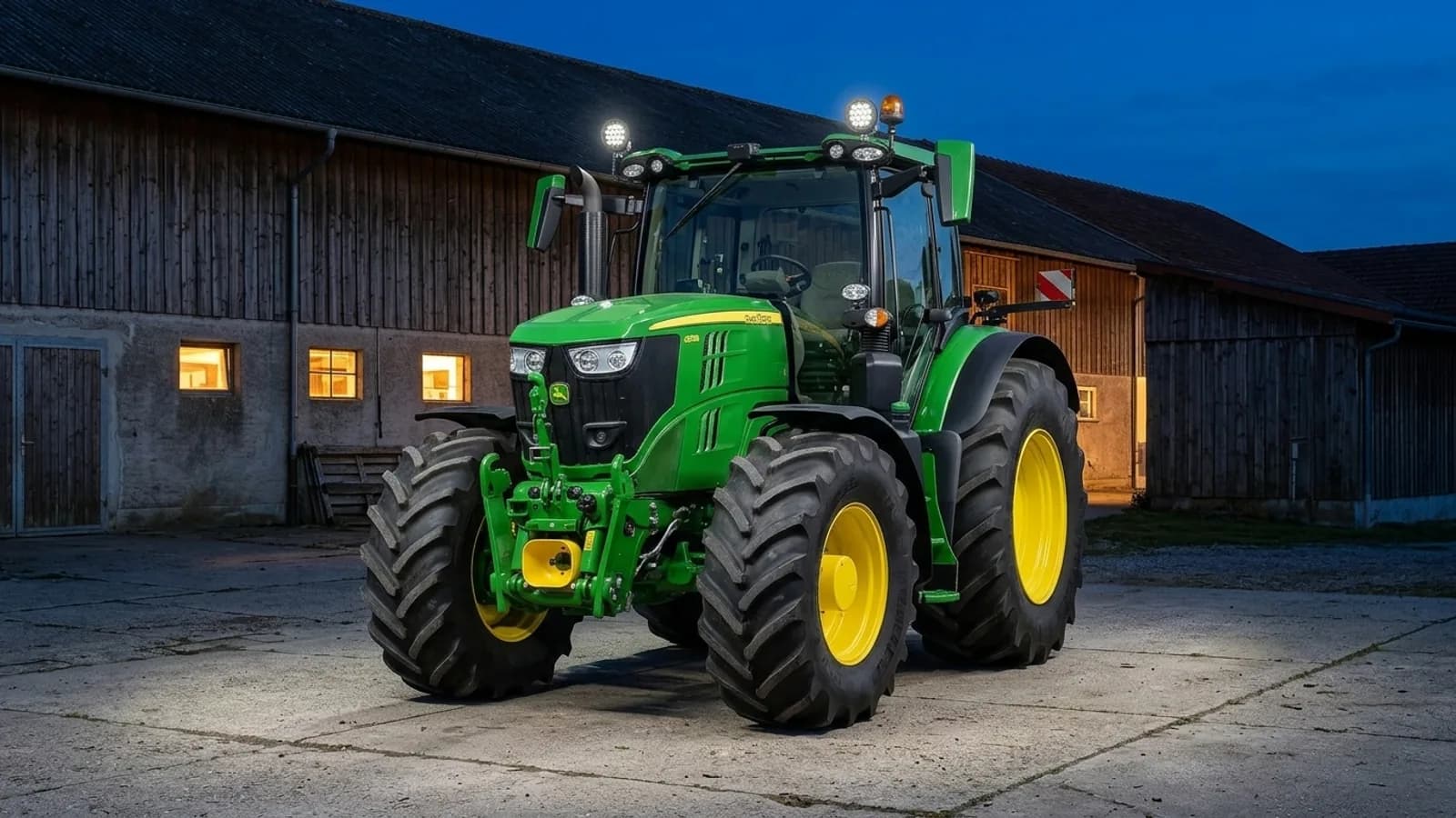 Tracteur John Deere dans la cour de ferme au soir, phares de travail LED Next-Tech sur le toit