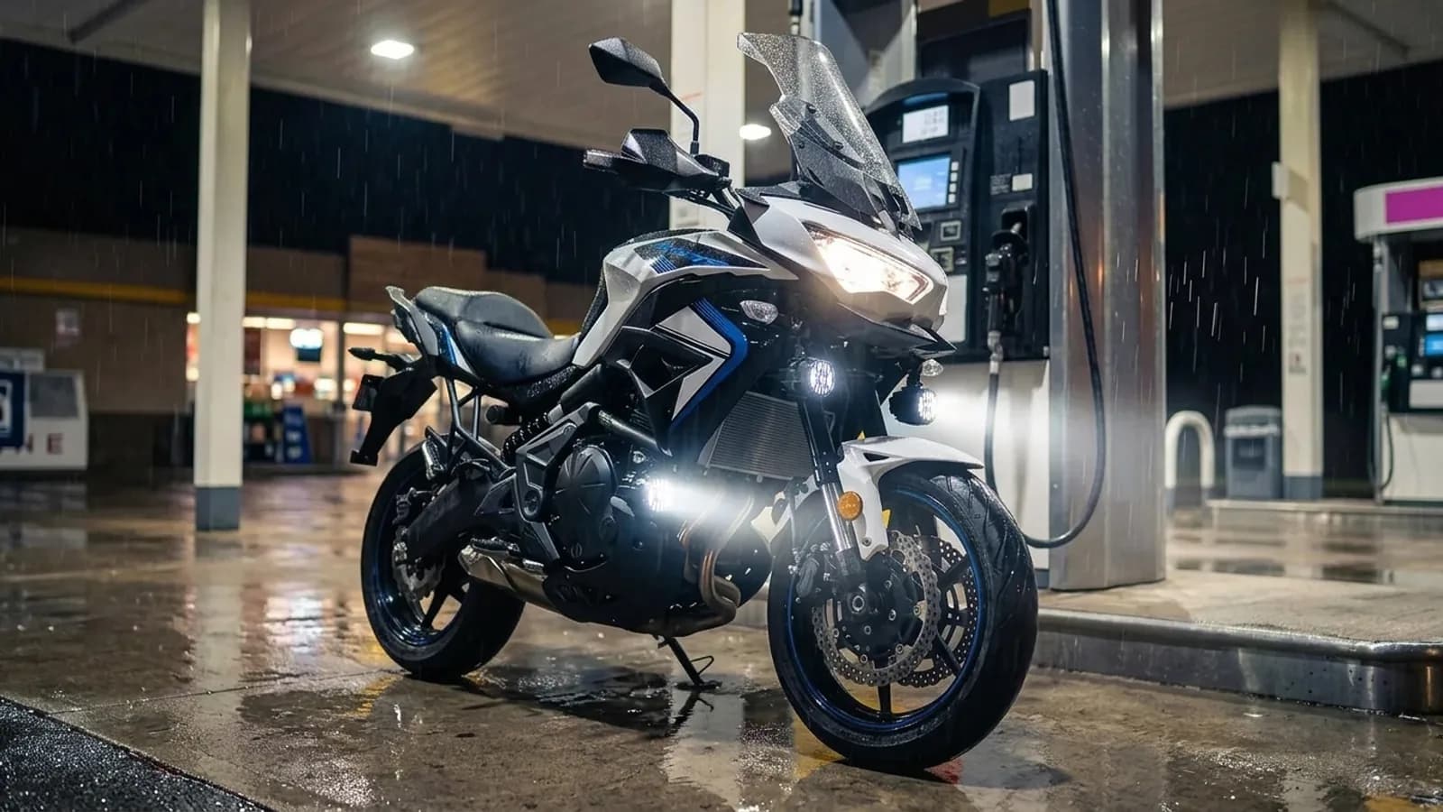Kawasaki Versys 650 sous l'auvent d'une station la nuit sous la pluie, feux additionnels LED Next-Tech allumés