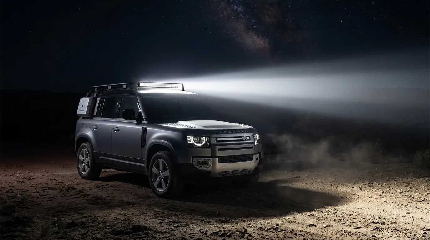Land Rover Defender en expédition nocturne, barre LED Next-Tech allumée éclairant la piste désertique