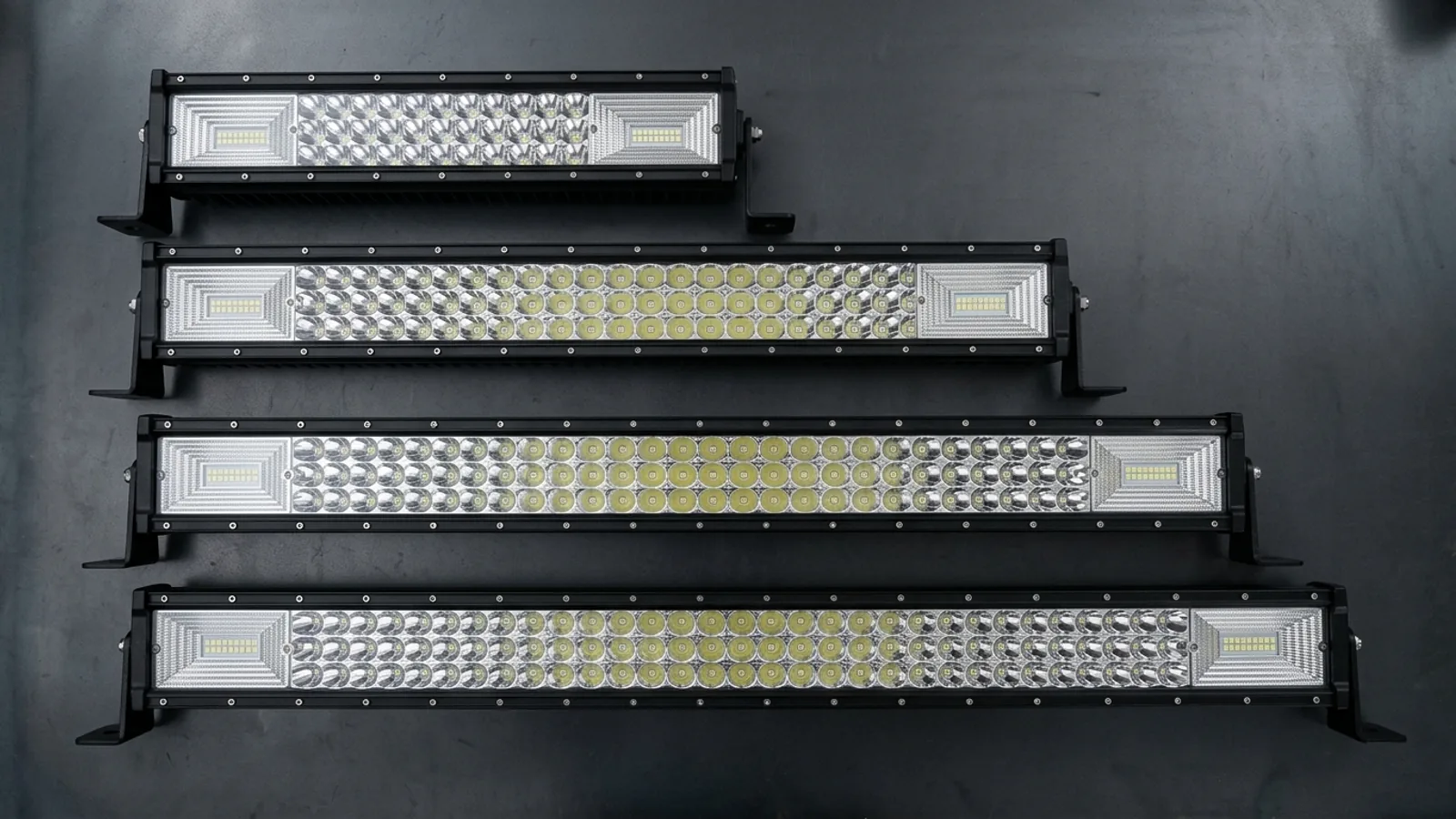 Quatre barres LED droites triple rangée Next-Tech de 55, 87, 105 et 125 cm alignées sur un établi sombre