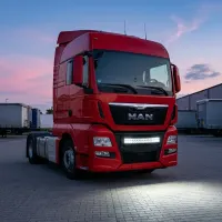 camion MAN rouge équipé d'une barre LED incurvée 24v 55cm 120w Next-Tech au niveau de la calandre, sur une zone de chargement