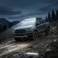 pick-up 4x4 noir équipé d'une barre LED incurvée Next‑Tech 180w 80cm allumée 13000 lumens en montée boueuse de nuit