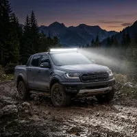 Pick-up Ford Raptor équipé d'une barre LED incurvée Next‑Tech 180w 80cm 13000 lumens allumée en tout-terrain boueux
