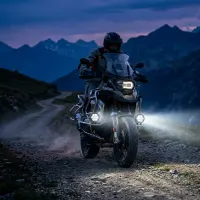 kit de feux LED ronds 110mm Next‑Tech 140w 18800 lumens 5000K ultra puissants installés sur moto trail roulant de nuit en montagne