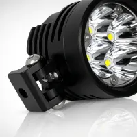 Gros plan d'un phare LED additionnel rond Next‑Tech 50W pour moto, optique à six diodes et fixation noire sur fond studio