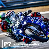 Moto de course bleue n°96 inclinée en virage sur circuit avec phares LED ronds Next‑Tech 50W allumés en blanc