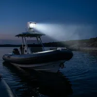 phare LED de recherche motorisé 360° Next‑Tech 120w 12500lm allumé sur bateau semi-rigide au crépuscule