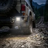 Feu LED de recul Next‑Tech allumé sous l'arrière d'un 4x4 sur piste boueuse au crépuscule, lumière blanche