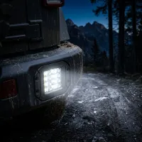 Feu LED de recul rectangulaire Next‑Tech encastré sur pare-chocs de 4x4 boueux, allumé en blanc sur un chemin forestier de nuit