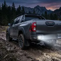 Feu LED de recul rectangulaire Next‑Tech 40W allumé en blanc sous le pare-chocs d'un pick-up 4x4 dans la boue au crépuscule