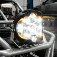 phare LED rond Next‑Tech 130w 18cm allumé avec son feu de jour ambré monté sur arceau dans un atelier
