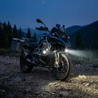 moto sur un chemin de montagne avec kit de phares LED longue portée 100w 60mm rond fixation crash bars et mode flash stroboscope  next-tech
