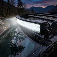 barre LED incurvée Next‑Tech 240W allumée sur galerie de toit de 4x4 boueux au crépuscule en montagne, lumière blanche 5000K