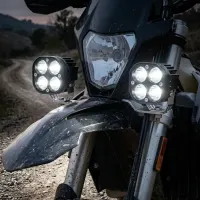 gros plan sur l'avant d'une moto trail sur piste au crépuscule équipée de feux LED carrés 50W Next‑Tech allumés blanc pur