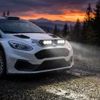 voiture de rallye blanche de face sur piste au crépuscule équipée de rampes LED Next‑Tech allumées en blanc pur