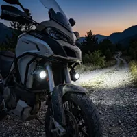 moto Ducati Multistrada de 3/4 sur piste au crépuscule équipée de feux LED antibrouillard Next‑Tech allumés blanc pur