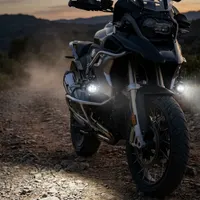 moto trail BMW GS de face sur piste au crépuscule équipée de feux LED antibrouillard Next‑Tech allumés en blanc pur