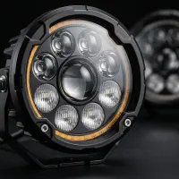 gros plan sur un phare LED rond Next‑Tech pour moto avec optiques et liseré orange sur fond studio noir