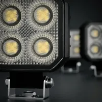 gros plan sur les 4 LED et l'optique carrée d'un phare de travail LED Next‑Tech 20W, second phare flou en arrière-plan
