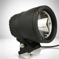 gros plan sur un phare LED longue portée rond Next‑Tech 25W en boîtier alu noir sur fond studio blanc, réflecteur poli visible