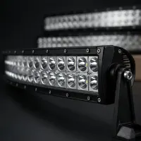 gros plan sur une barre LED incurvée double rangée Next‑Tech à lentilles réflecteurs, avec modèles similaires flous en fond studio noir