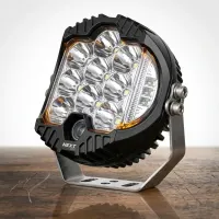 phare LED rond Next‑Tech 90W 120mm 15000lm avec feu de position orange sur établi bois, il est orienté vers le haut